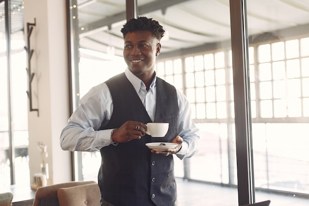 Hombre negro en una camisa azul de pie en un café
