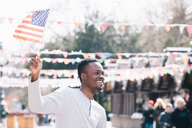 Hombre negro feliz ondeando la bandera estadounidense