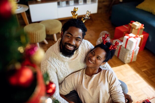 Hombre negro feliz y su esposa relajándose en Navidad en casa