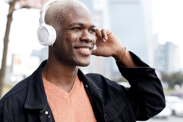 hombre negro guapo con auriculares retrato al aire libre