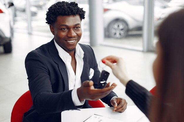 Hombre negro guapo y elegante en un salón del automóvil