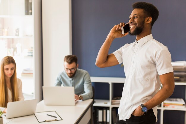 Hombre negro habiendo hone conversación cerca de colegas