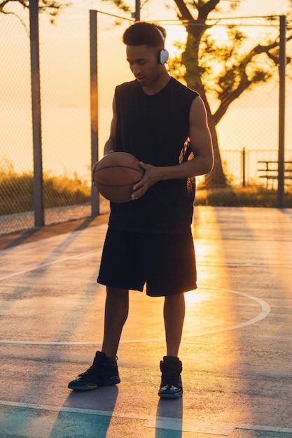 Hombre negro haciendo deporte, jugando baloncesto al amanecer, estilo de vida activo, mañana soleada de verano