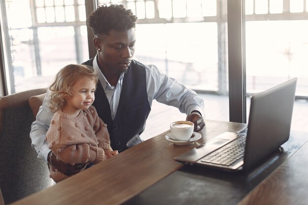 Hombre negro con hija blanca de pie en un café