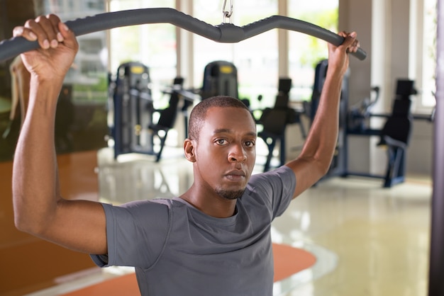 Hombre negro que ejercita en la máquina lat pull down