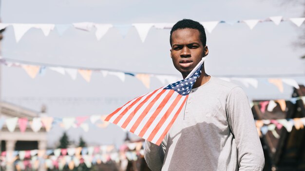 Hombre negro que sostiene la bandera estadounidense y mirando a cámara