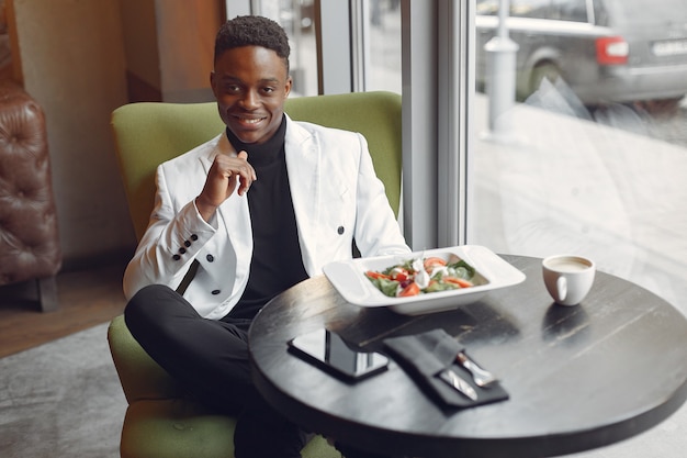 Hombre negro sentado en un café y comiendo una ensalada de verduras