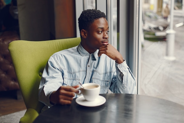 Hombre negro sentado en una cafetería y tomando un café