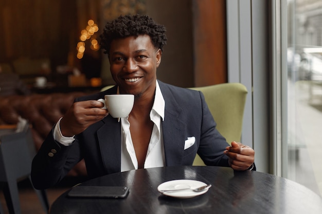 Hombre negro sentado en una cafetería y tomando un café