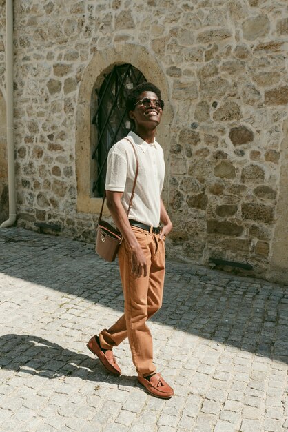 Hombre negro sonriente de tiro completo caminando al aire libre