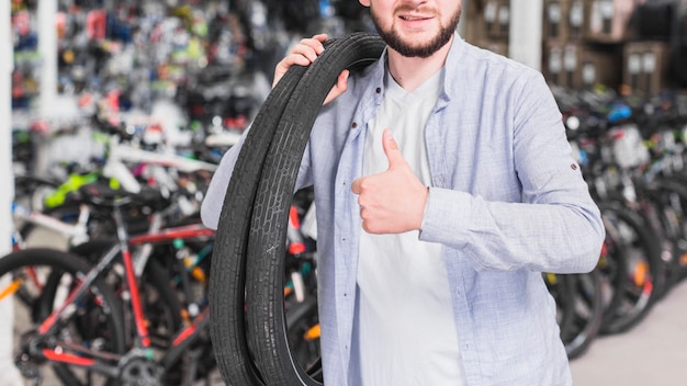 Foto gratuita hombre con neumáticos de bicicleta gesticulando pulgar arriba