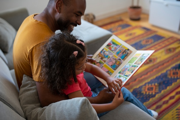 Foto gratuita hombre y niña de alto ángulo leyendo cómics en casa