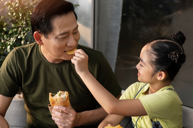 Hombre y niña de tiro medio tomando un descanso para almorzar al aire libre