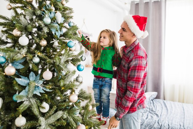 Hombre y niña tocando árbol de navidad