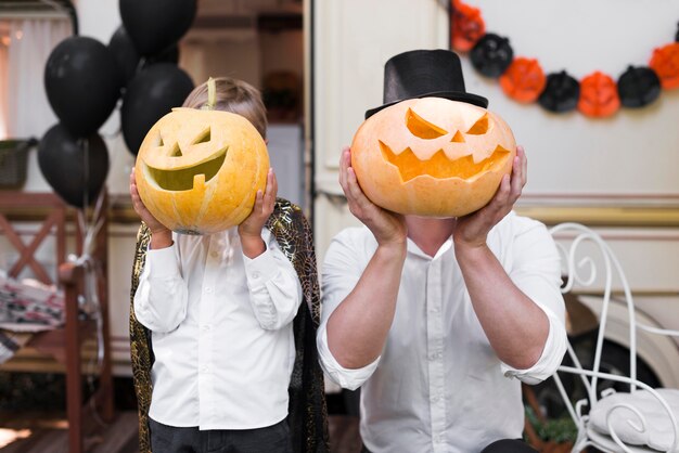 Hombre y niño sosteniendo calabazas talladas