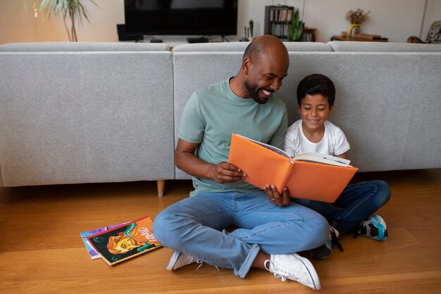 Hombre y niño de tiro completo leyendo cómics en casa