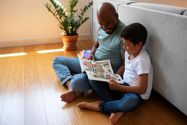 Foto gratuita hombre y niño de tiro completo leyendo cómics en casa