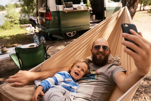 Hombre y niño tomando selfie en hamaca alto ángulo