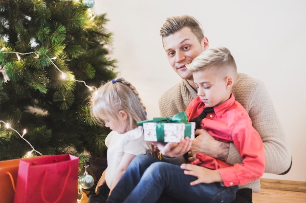 Foto gratuita hombre con niños al lado de árbol de navidad