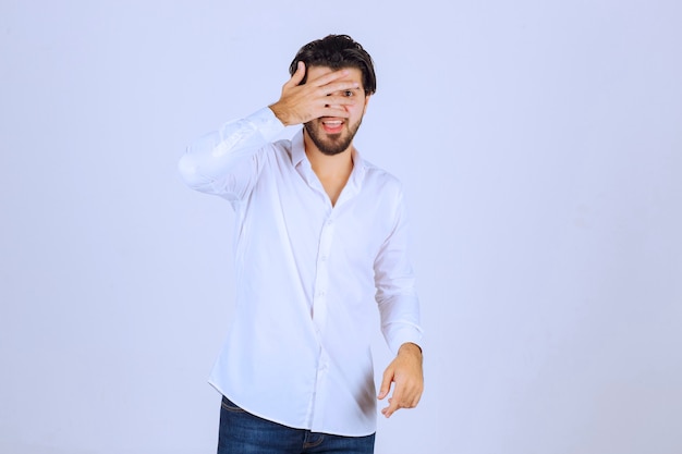 Hombre observando el exterior a través de sus dedos u ocultando su rostro.