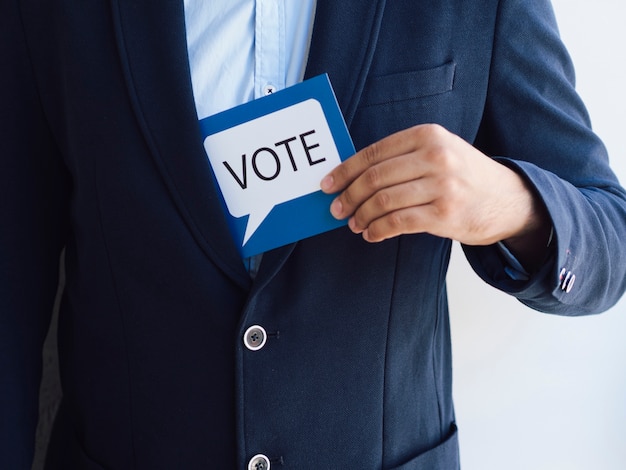 Foto gratuita hombre obteniendo una tarjeta de votación de su chaqueta