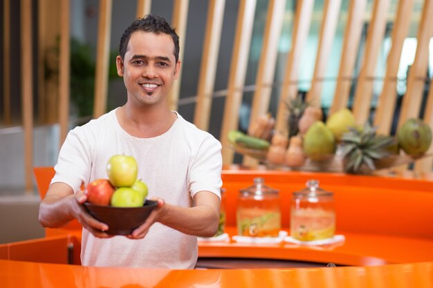 Hombre ofreciendo un bol con manzanas