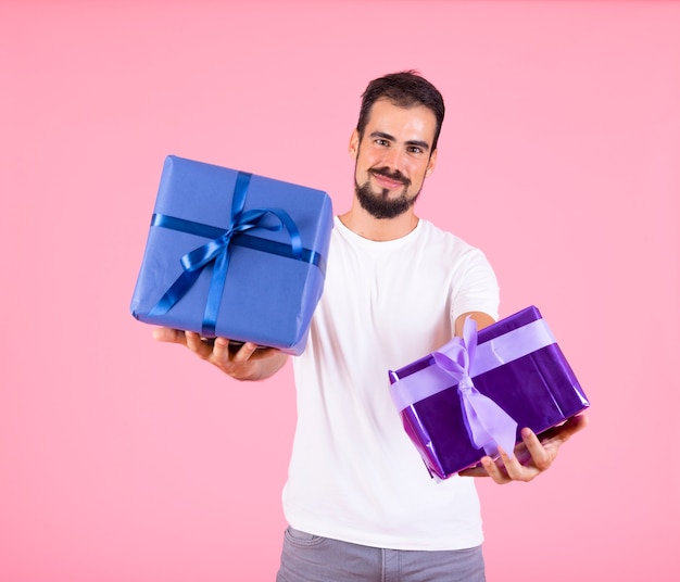 Foto gratuita hombre ofreciendo regalo envuelto sobre fondo rosa