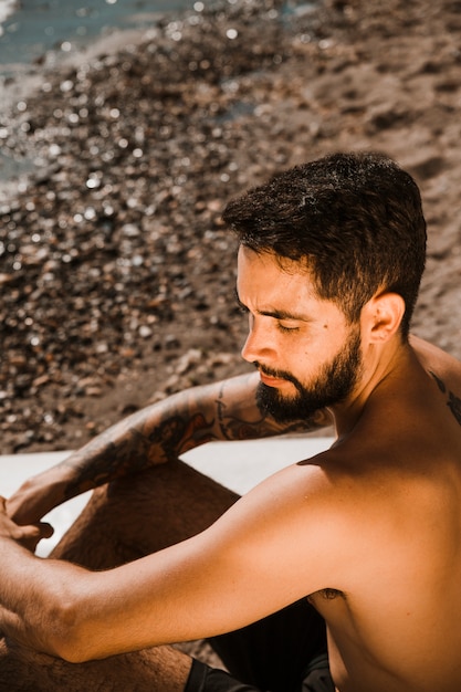 Hombre con los ojos cerrados cerca de la tabla de surf