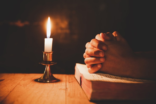 hombre orando en la Biblia en las velas ligeras enfoque selectivo