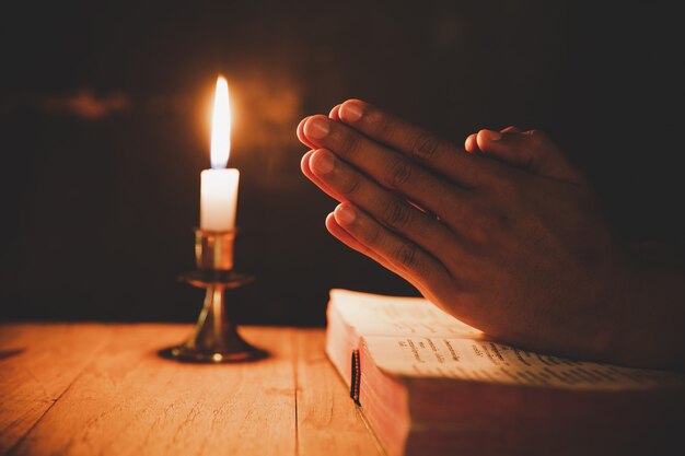 hombre orando en la Biblia en las velas ligeras enfoque selectivo