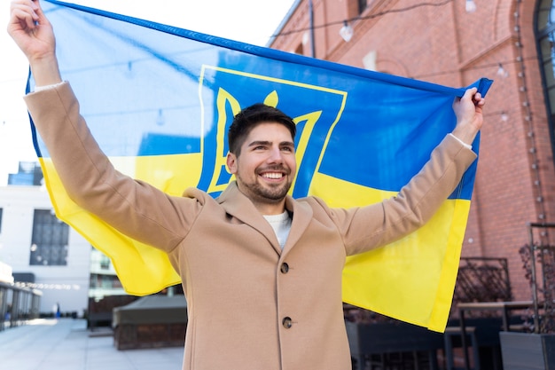 Hombre orgulloso de tiro medio que sostiene la bandera ucraniana