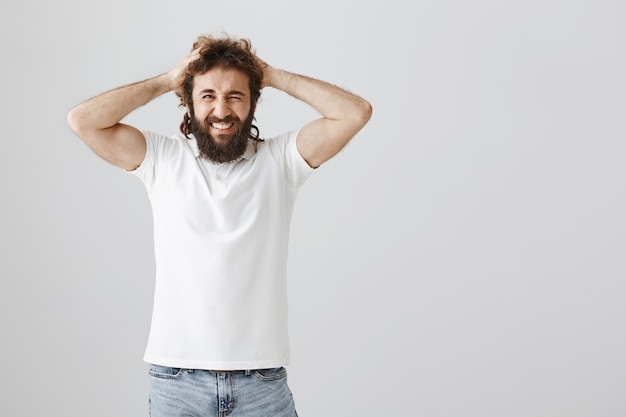 Hombre de Oriente Medio frustrado y molesto tira el pelo y hace muecas