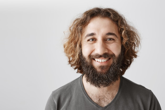 Foto gratuita hombre de oriente medio sonriente complacido que parece feliz y encantado