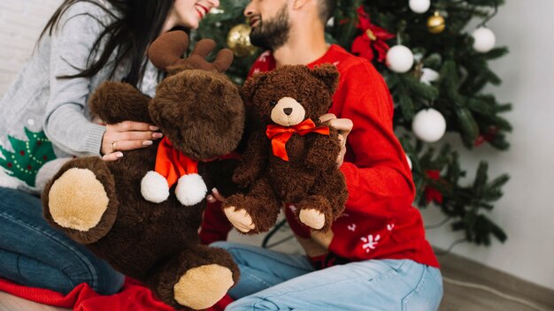 Hombre con oso de peluche cerca de mujer con ciervo esponjoso