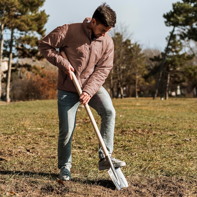 Foto gratuita hombre con pala para cavar un hoyo para plantar un árbol