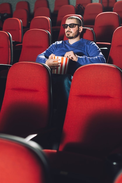 Hombre con palomitas de maíz en el auditorio vacío