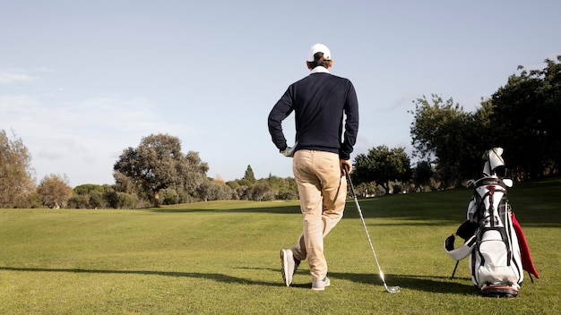 Hombre con palos de golf y espacio de copia en el campo