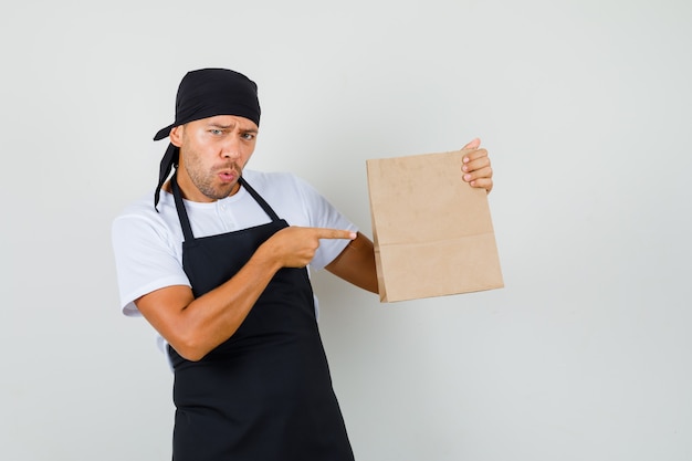 Hombre panadero apuntando a la bolsa de papel en la camiseta