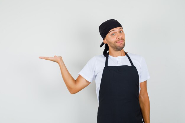 Hombre panadero levantando la palma como sosteniendo o mostrando algo en la camiseta