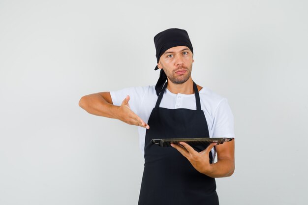 Hombre panadero mostrando bandeja metálica en camiseta