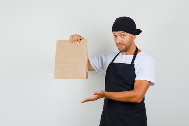 Foto gratuita hombre panadero mostrando bolsa de papel en camiseta