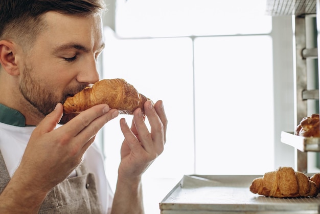 Hombre panadero sosteniendo croissants en la panadería