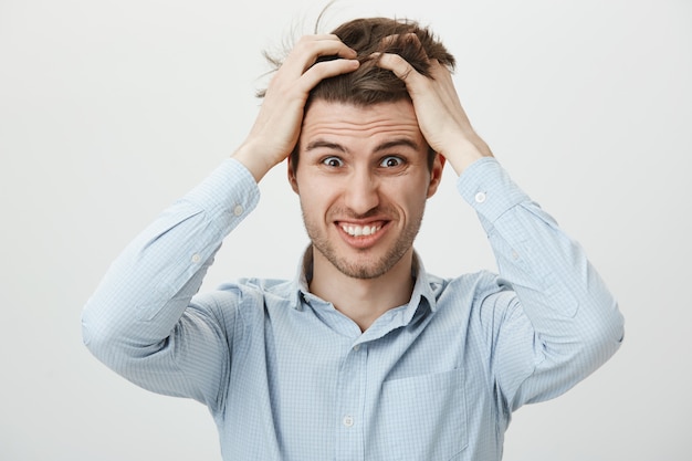 Foto gratuita hombre en pánico sintiéndose preocupado, agitando el cabello alarmado