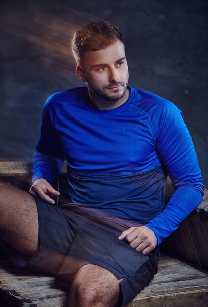 Un hombre con pantalones cortos y camiseta deportiva azul. en el estudio