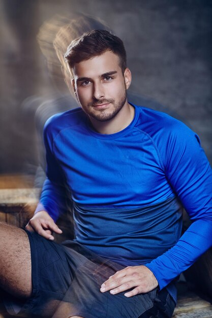 Un hombre con pantalones cortos y camiseta deportiva azul. en el estudio