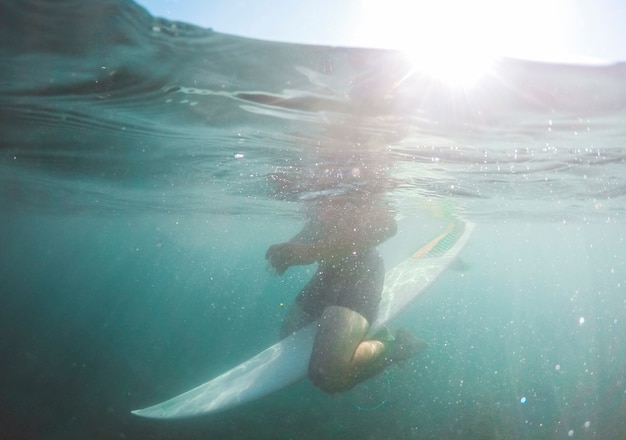 Hombre en pantalones cortos sentado en la tabla de surf en el agua