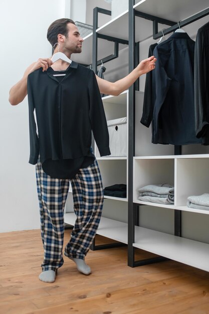 Hombre en pantalones de cuadros escoceses eligiendo una camisa para usar