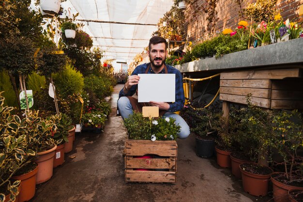 Hombre con papel cerca de la caja con flores