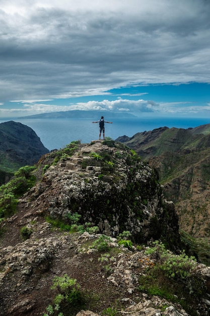 Foto gratuita hombre parado en la colina contra el fondo del hermoso paisaje montañoso