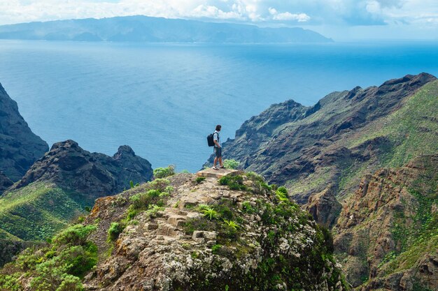 Hombre parado en la colina contra el fondo del hermoso paisaje montañoso